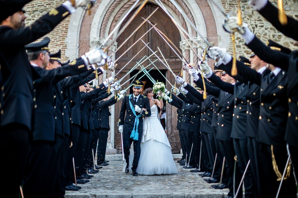 The couple pass beneath the arch of sabres held by officers in uniform.