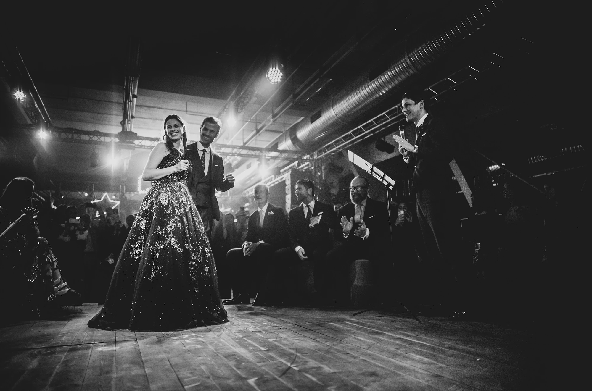 In a dark gown, among the guests who ring them.