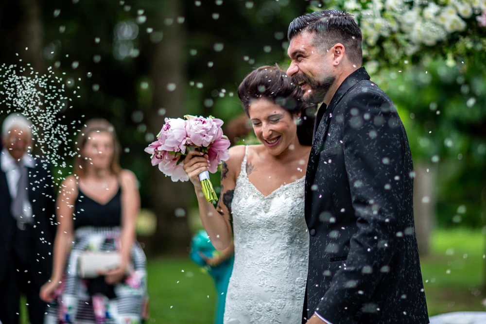 In the garden, the couple laugh under the shower of rice.