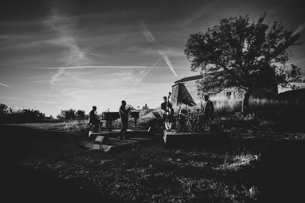 In the field, the musicians set up beside the lone tree.
