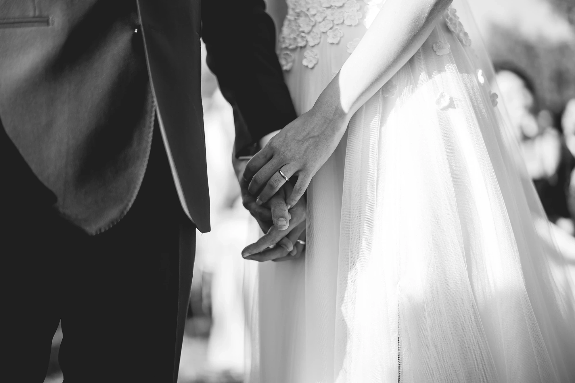 Hands joined between the jacket and the dress.