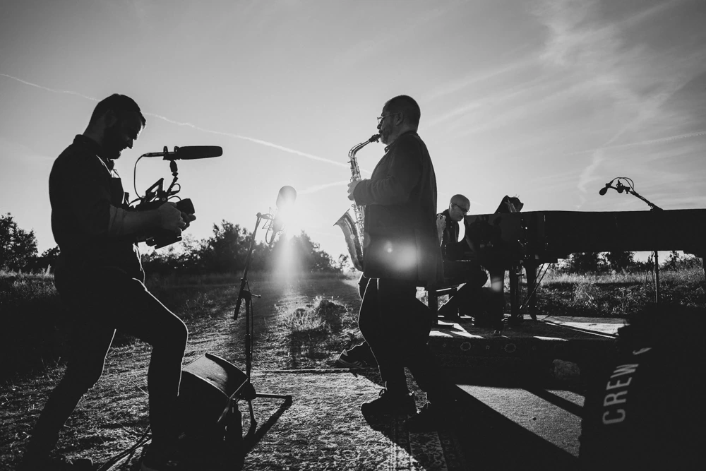Backlit: a cameraman films the saxophonist in the low sun.