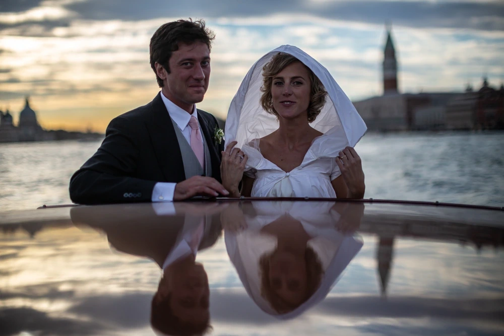 On the boat in the lagoon, the couple reflected in the roof, the campanile beyond.
