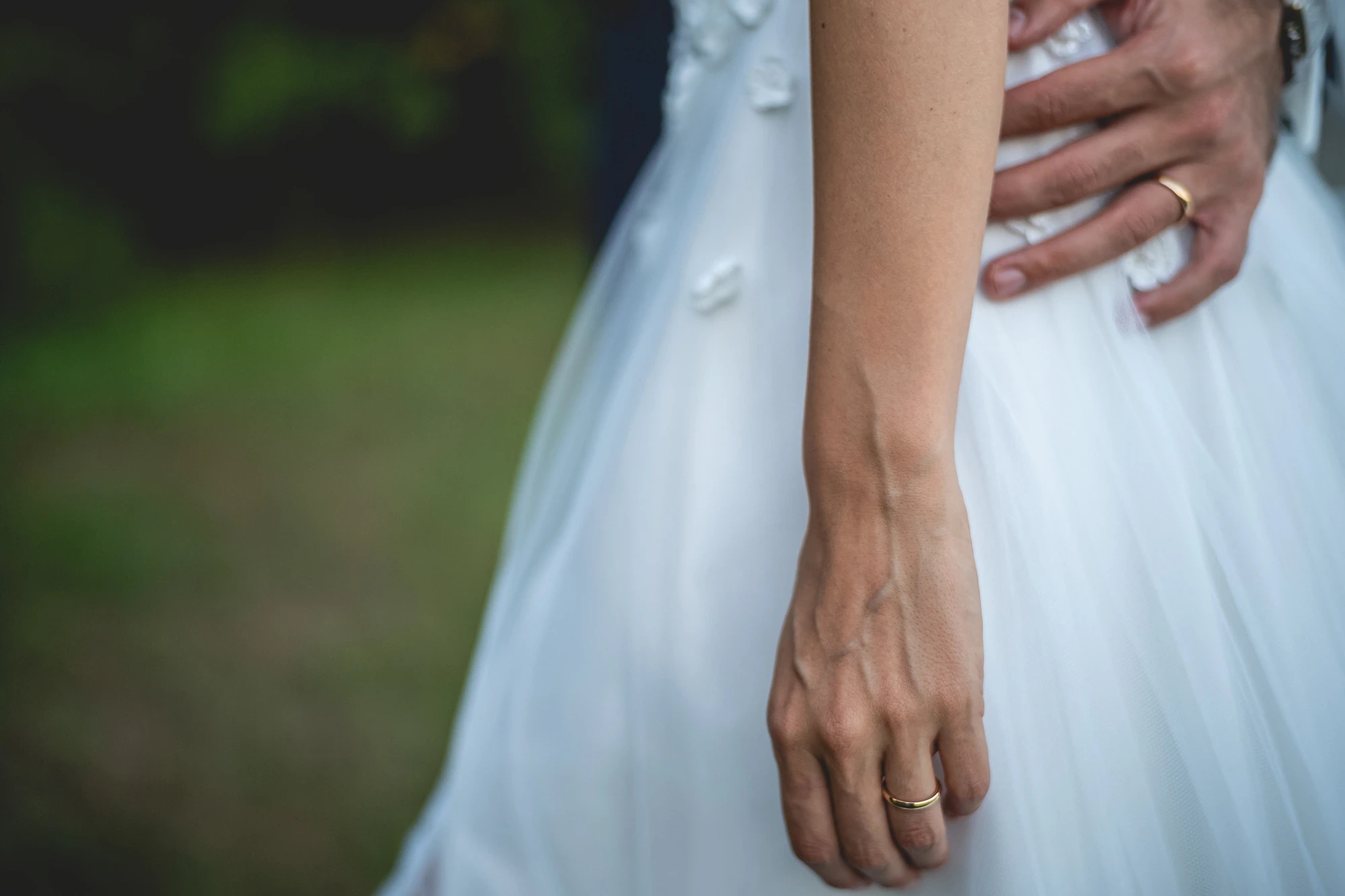 Hands at her side: the ring on her finger, his hand resting at her waist.
