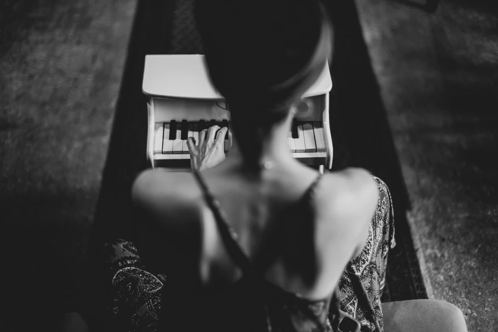 From behind, hands on the keyboard beyond a bare shoulder.