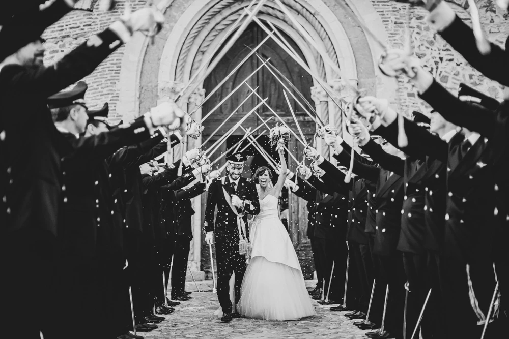 At the doorway, arms raised beneath the sabres.