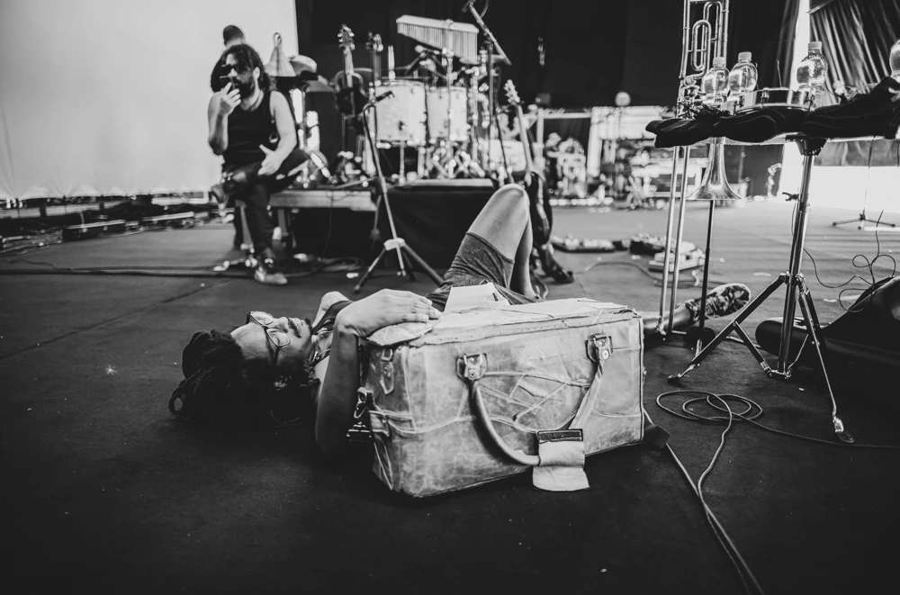 On stage, an open case on the floor and someone lying down to rest.