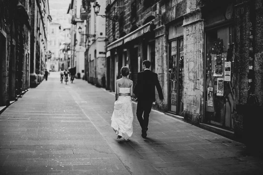 From behind, the couple walk away down the street.