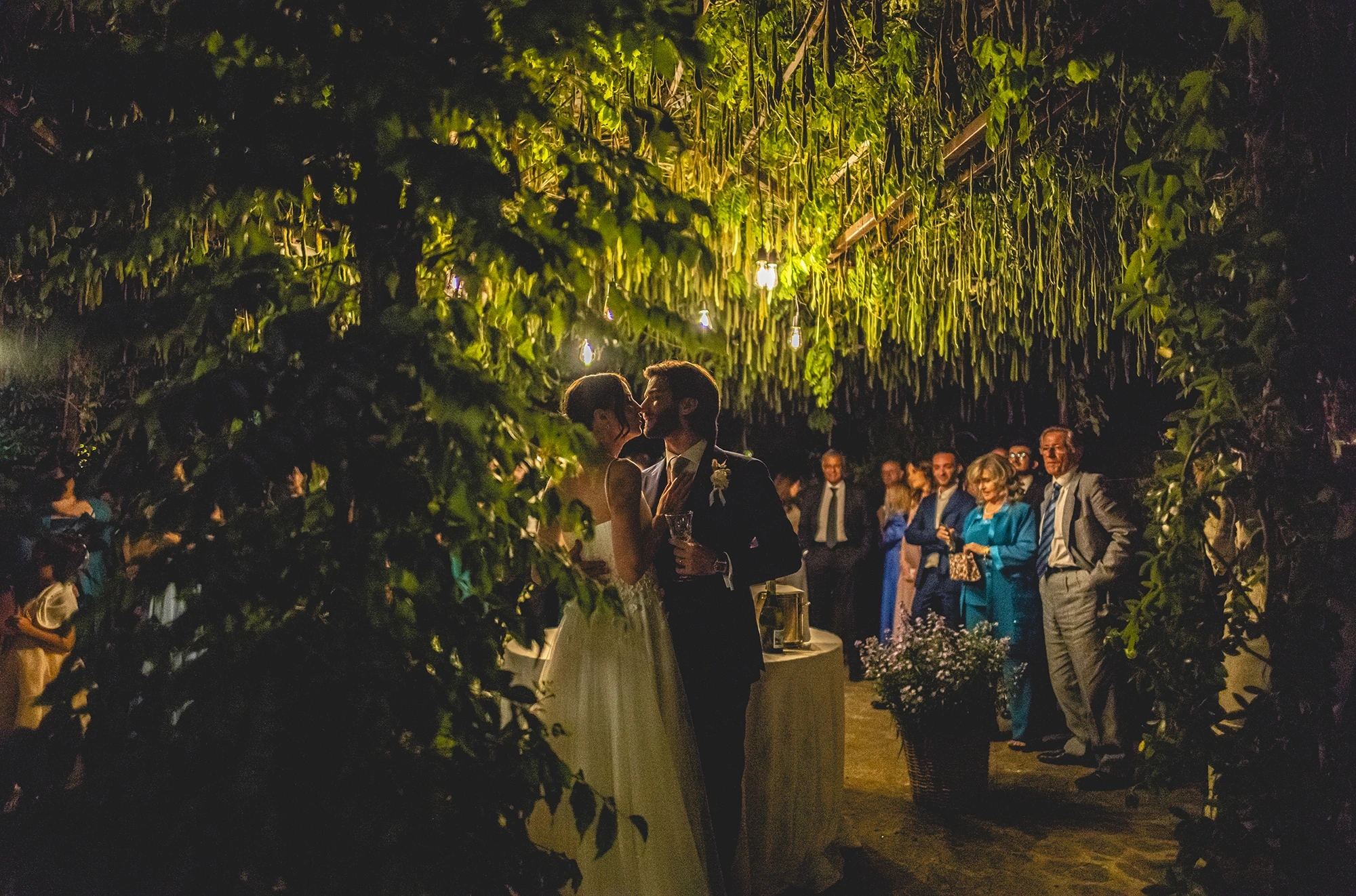Between walls of greenery, the couple and guests by candlelight.