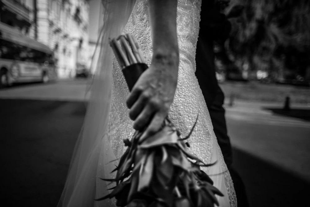 The bouquet held at her side, in the middle of the road.