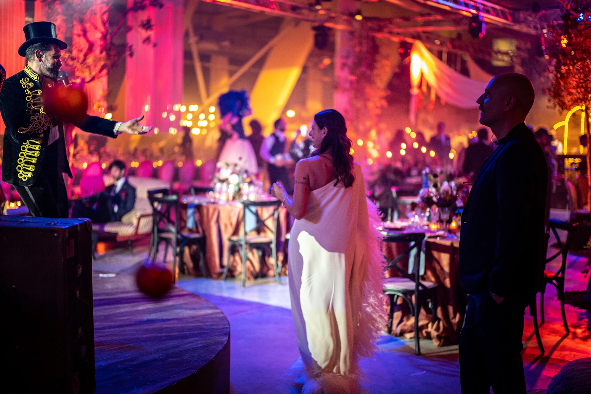 A performer in top hat and tails points; the bride watches him.