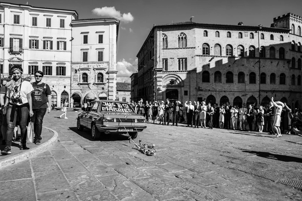 In the square, the couple's car between the lined-up guests.