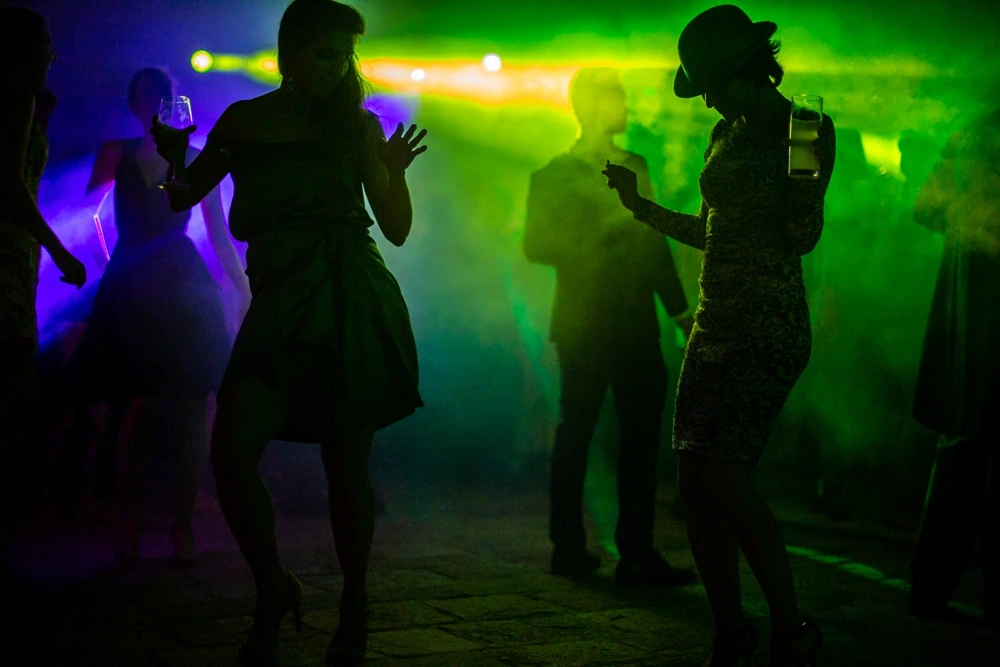 Silhouettes dancing in green and purple smoke.