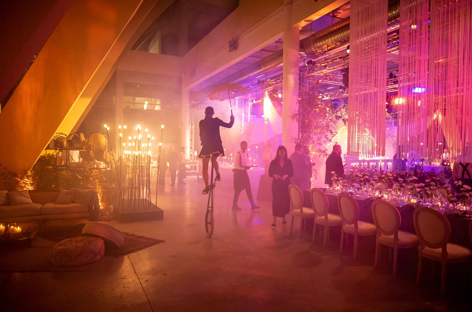 In the pink-smoked hall, a figure balanced on a unicycle.