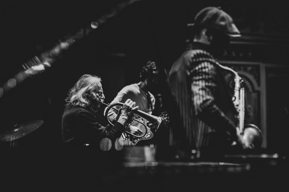 The musicians pressed together on stage around the trumpet.