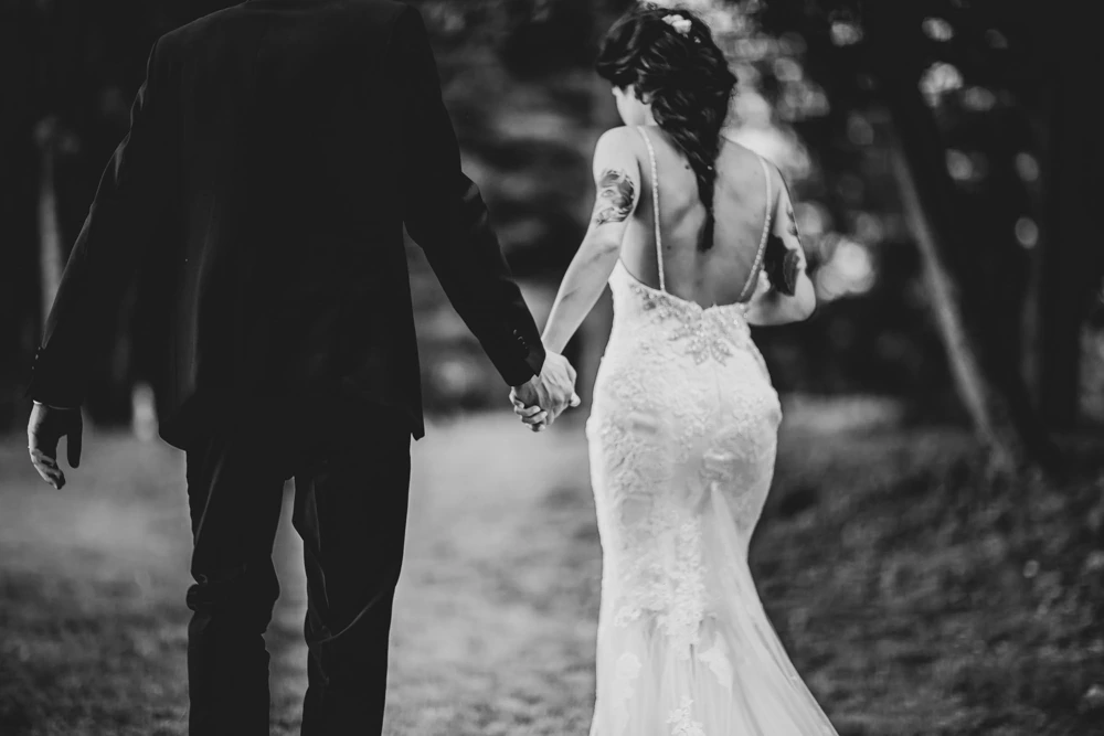 From behind, hand in hand, the open back of the dress.
