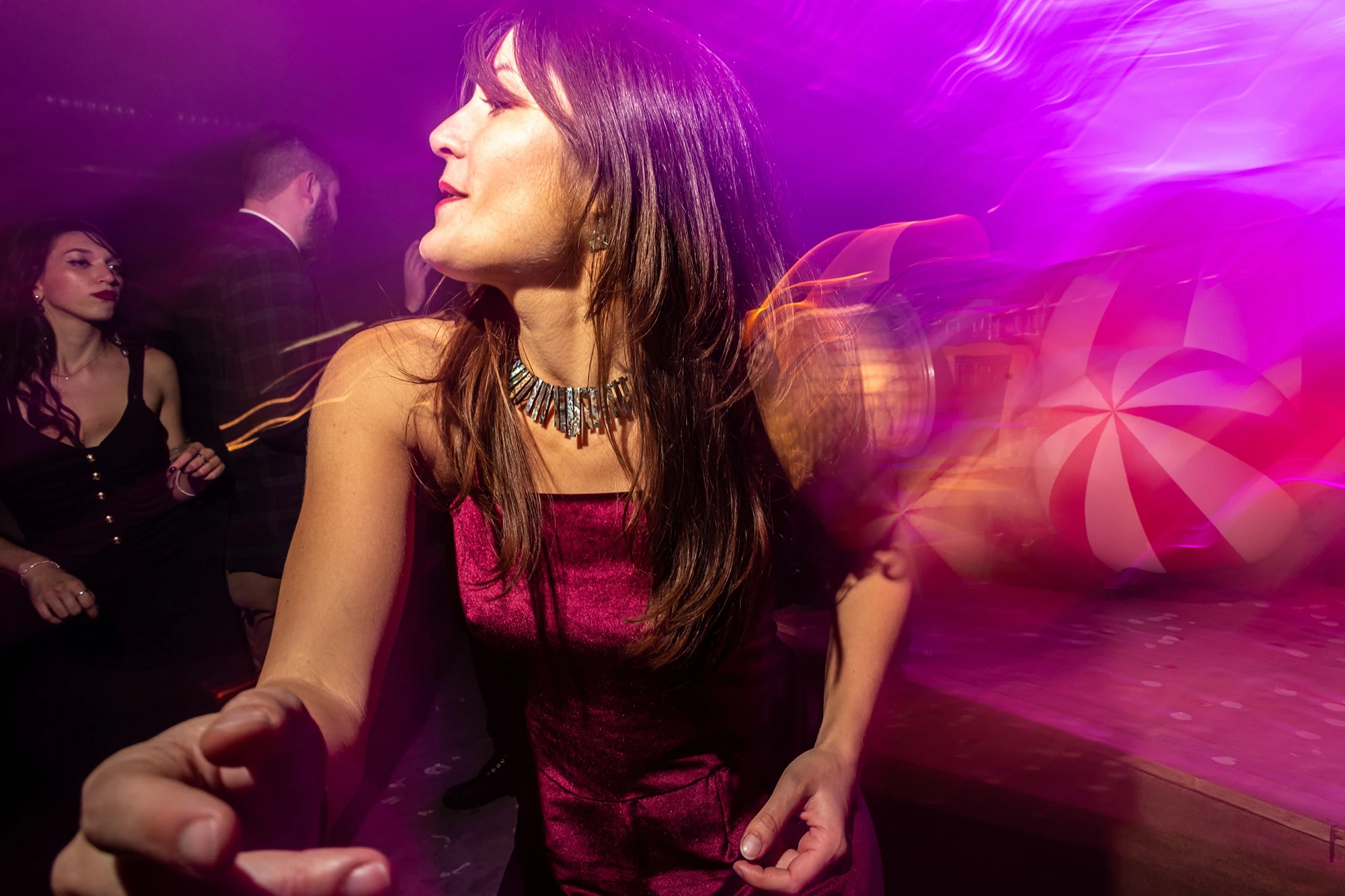 In a magenta dress, dancing in pink light.
