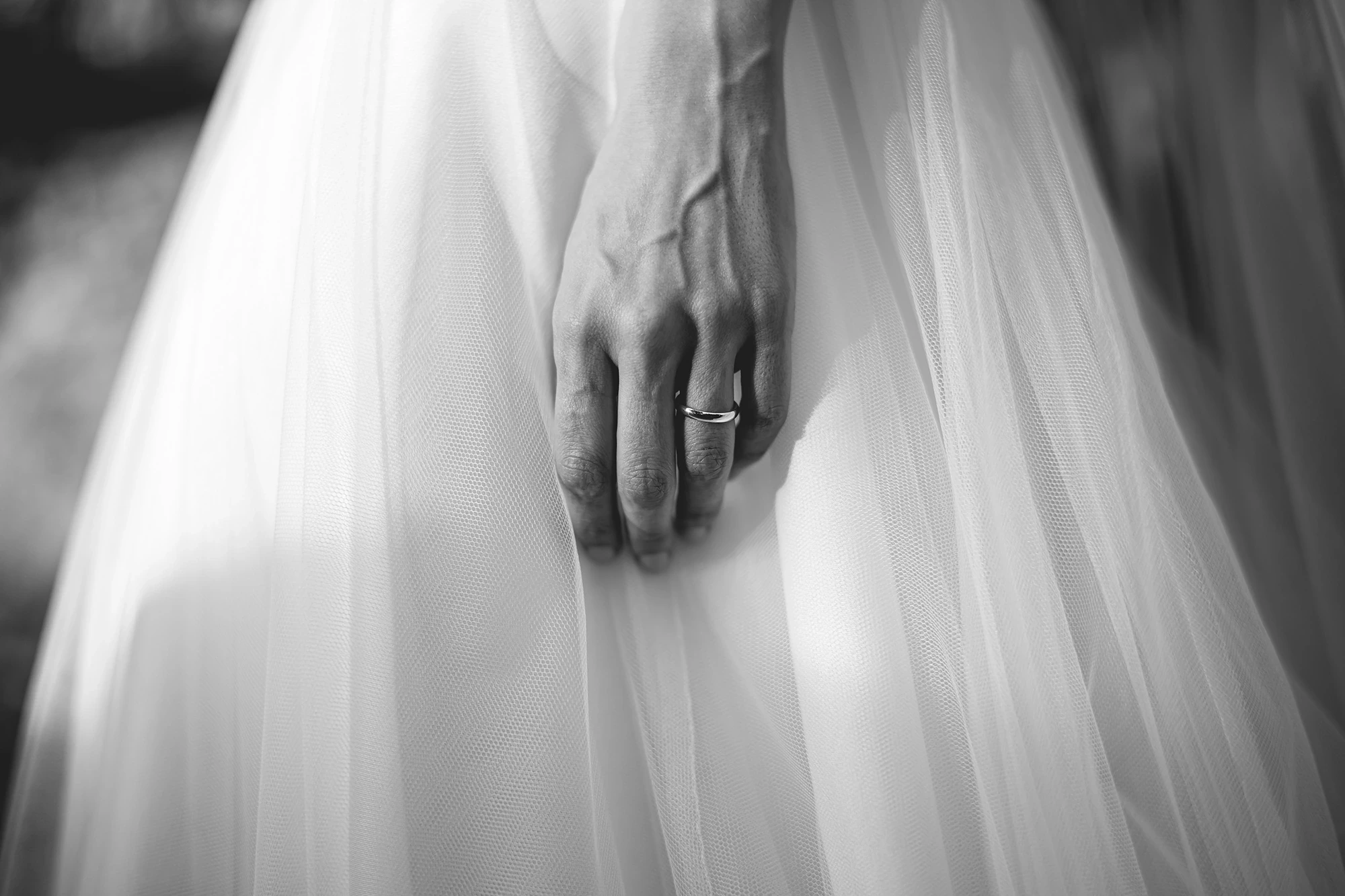 A hand with the wedding ring resting on the dress.