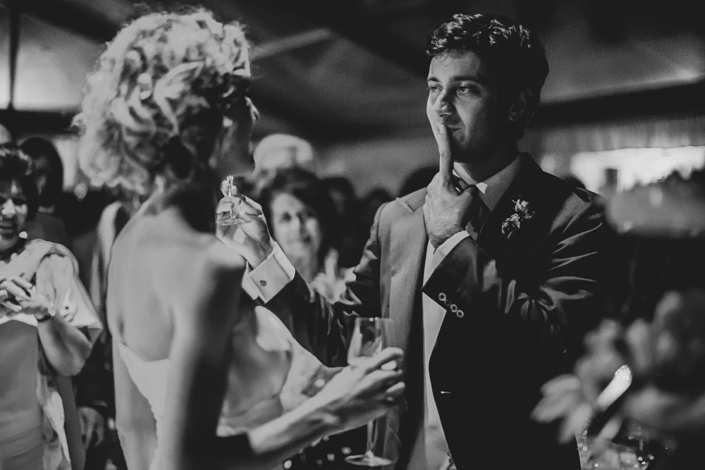 Among the guests, the groom raises a hand to his face.