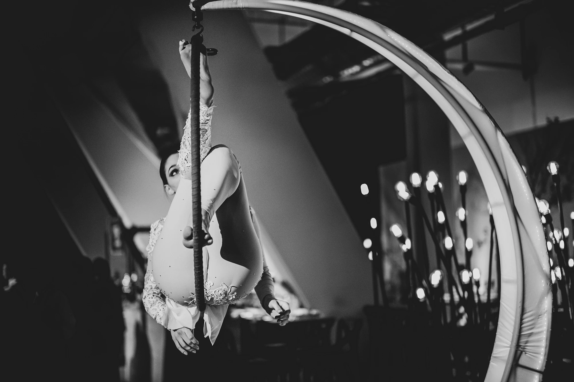 An aerialist upside down along the pole.