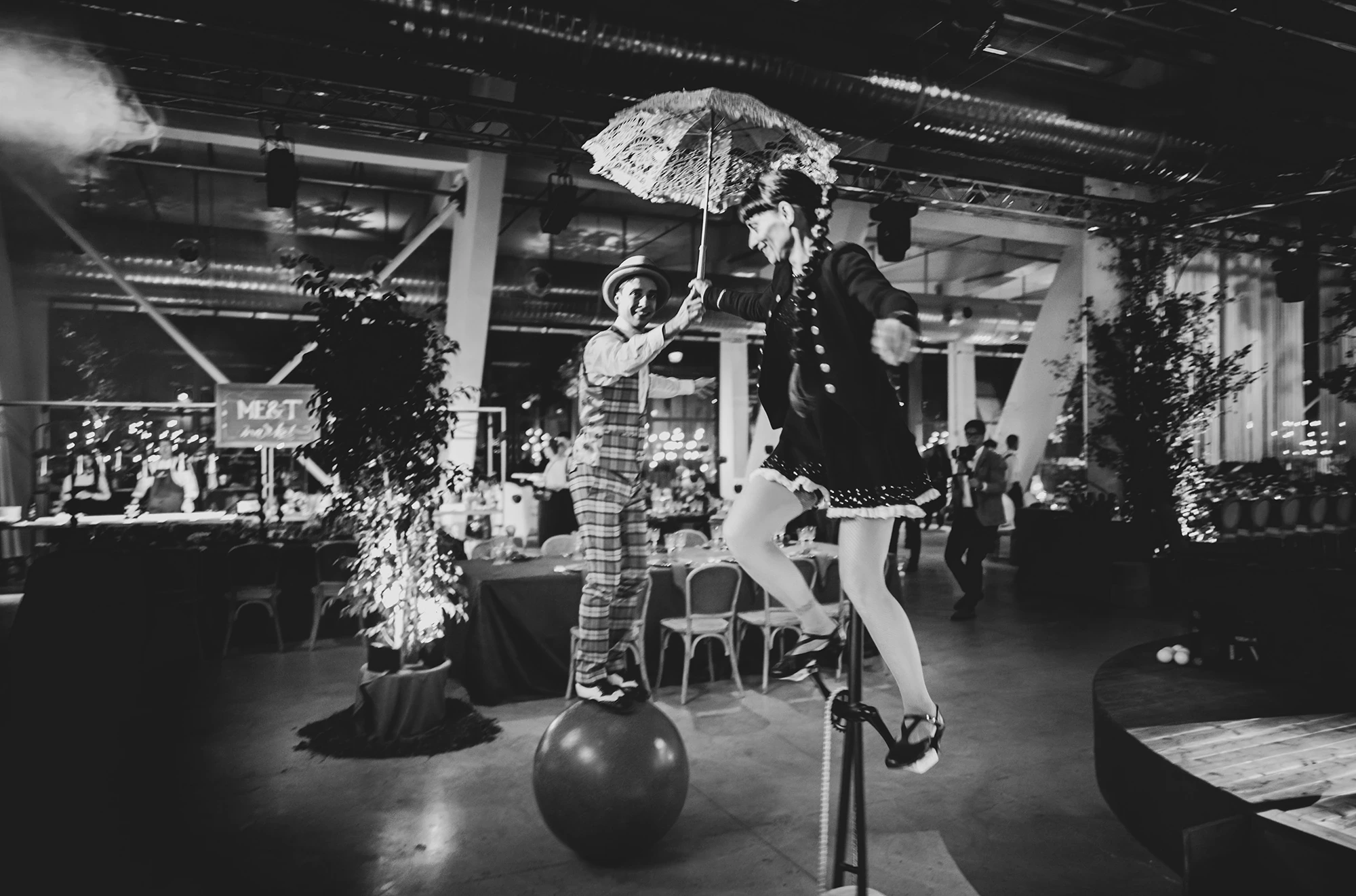 A performer balanced on a ball, parasol open.
