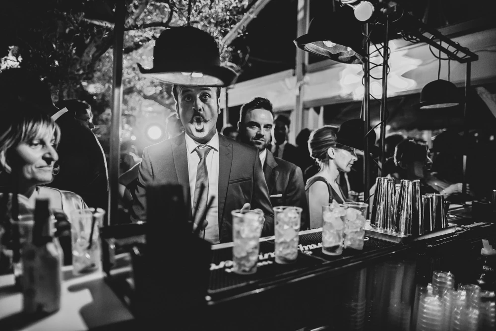 At the bar, the glasses ready and a man in a bowler hat.