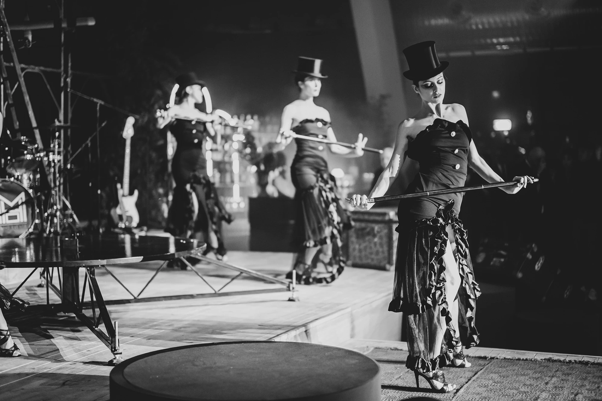 On the stage, performers in top hats and corsets with canes.