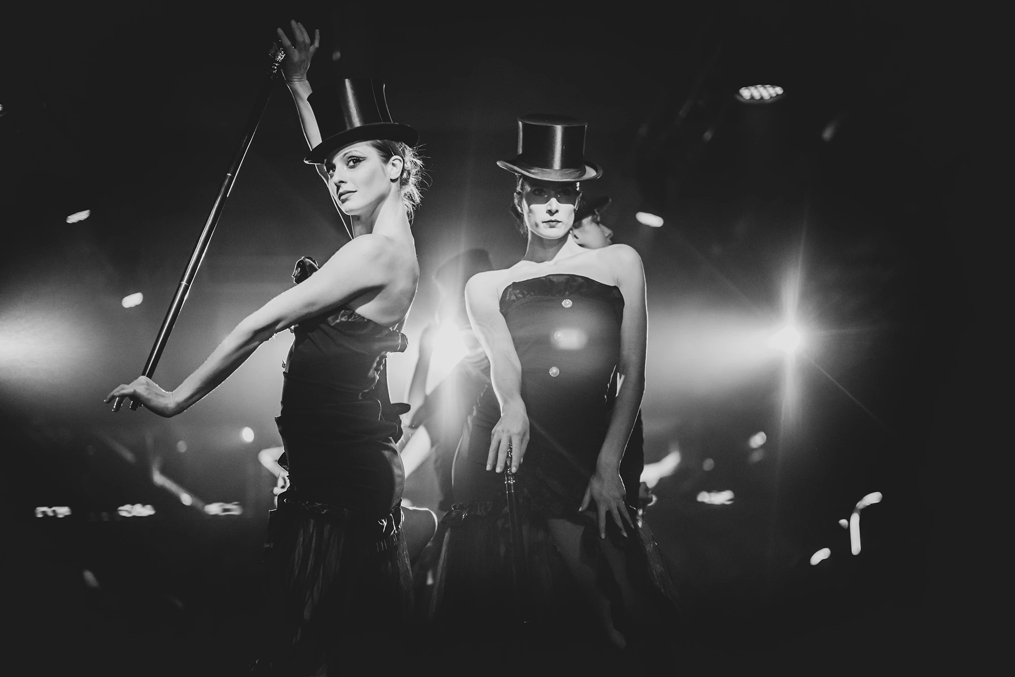 Two performers in top hats backlit, canes in hand.