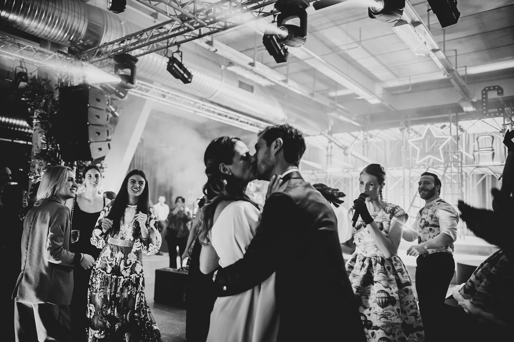 A kiss among the guests, in the industrial hall.