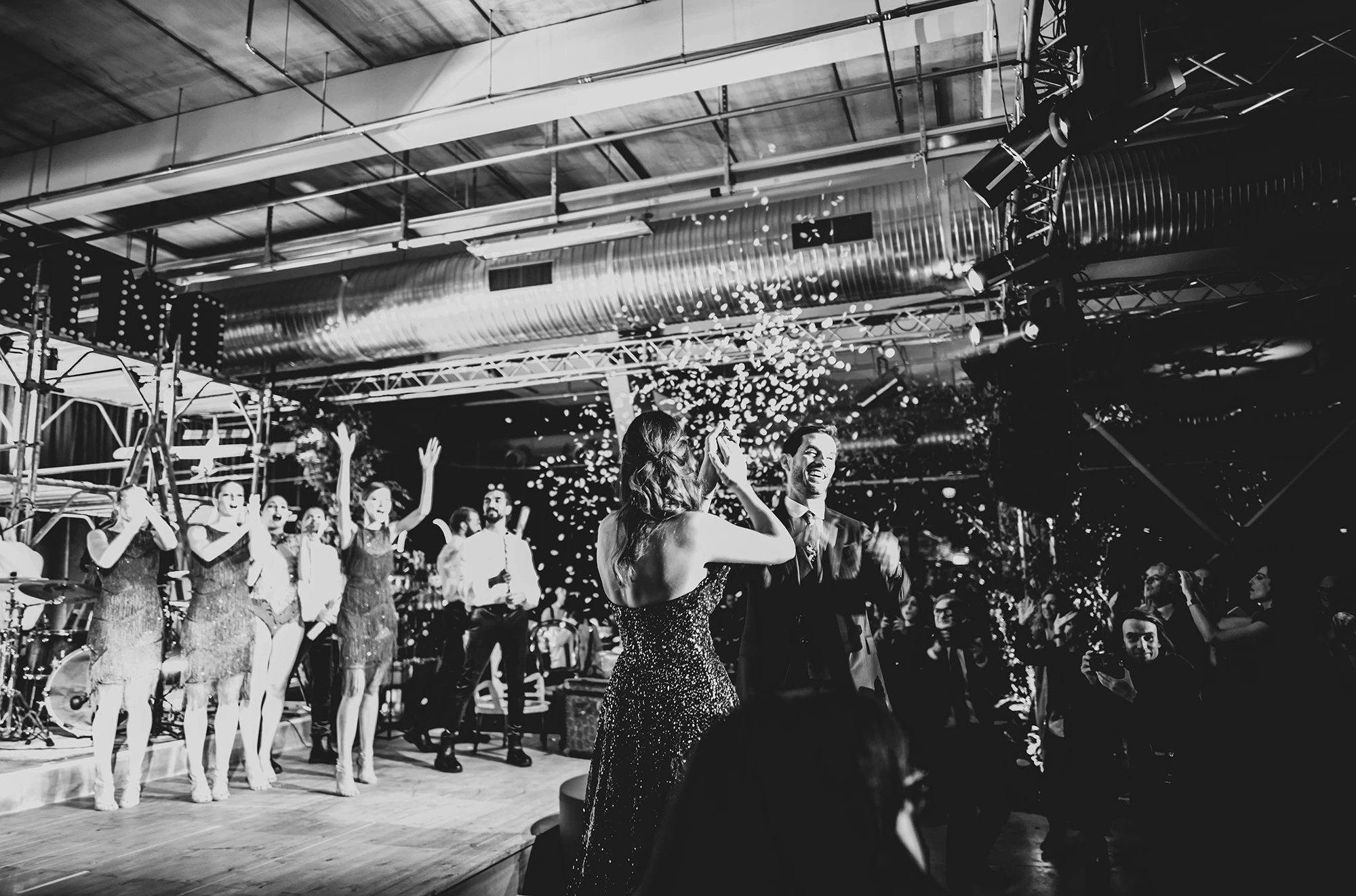 From behind, arms raised and confetti in the air.