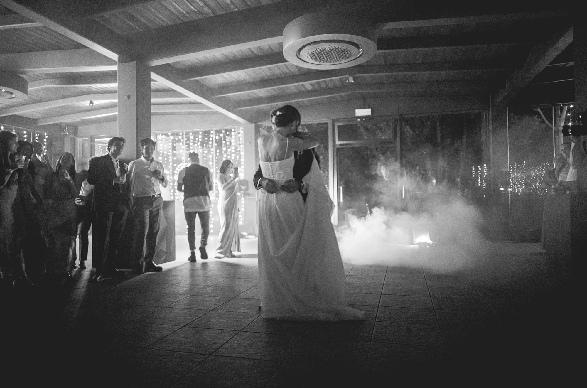 From behind, the bride steps into the cloud of smoke.