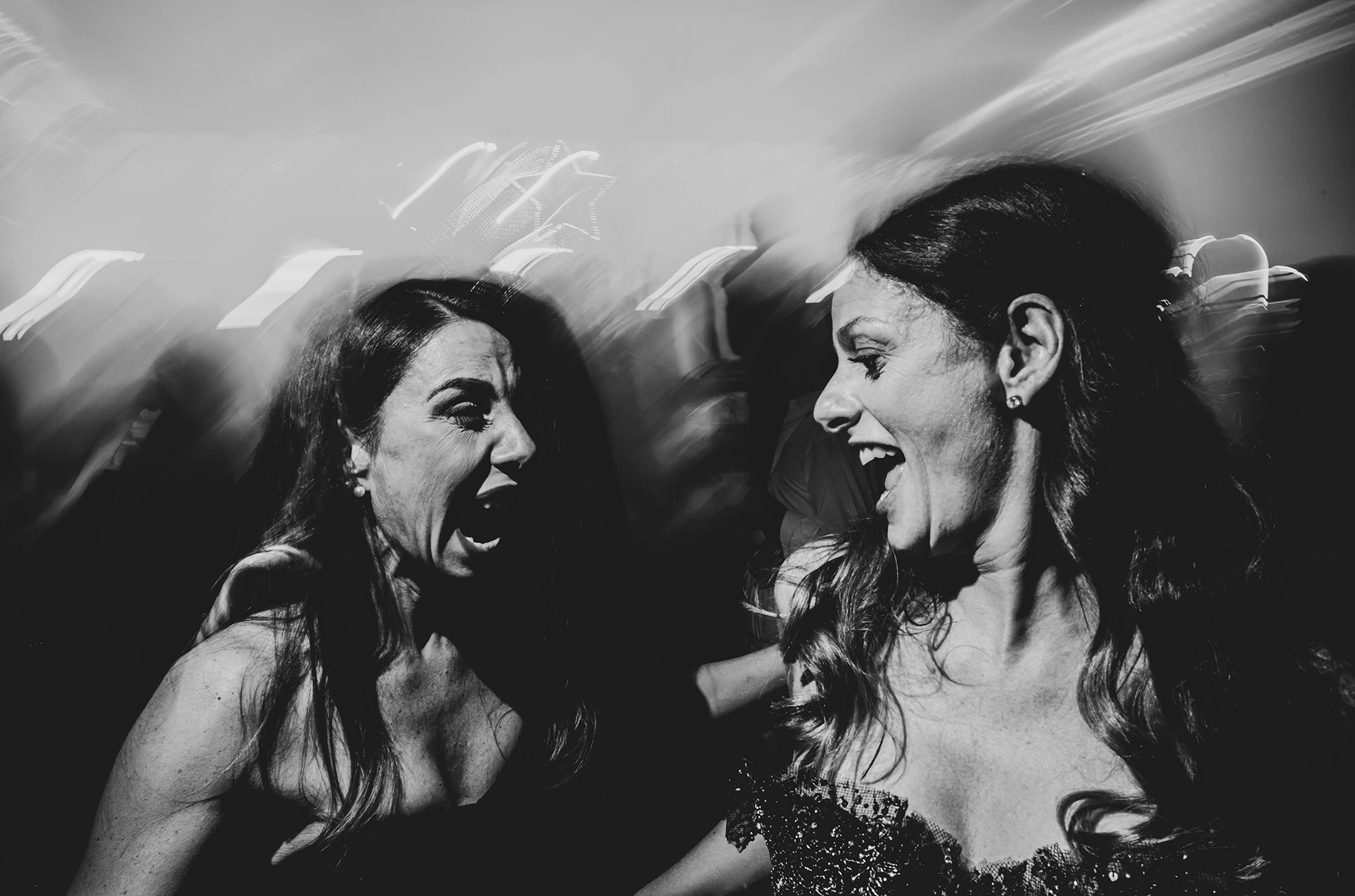 Two women singing out loud, the movement blurred.
